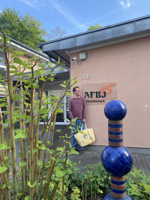 "Thilo steht mit der Einkaufstasche vor dem AFBJ-Wohnhaus"