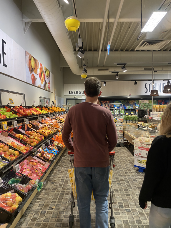 "Thilo beim Einkaufen im REWE vor der Obsttheke mit dem Einkaufswagen in der Hand."